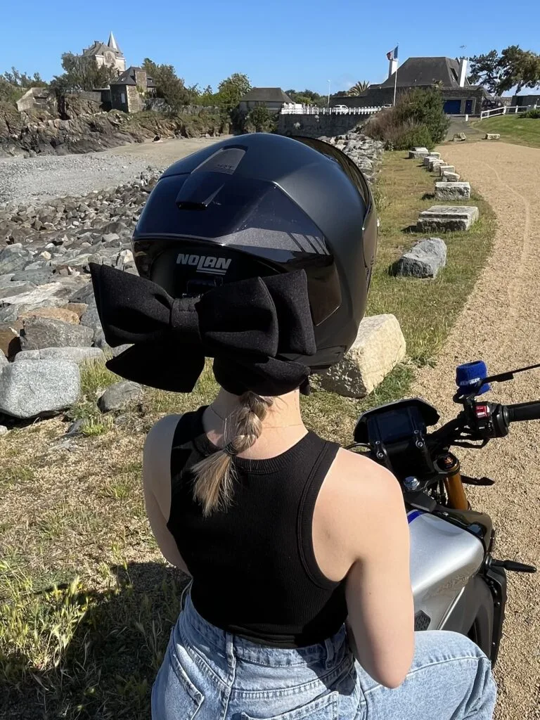 Photo de Noleen : nœud noir porté sur un casque près d’une moto